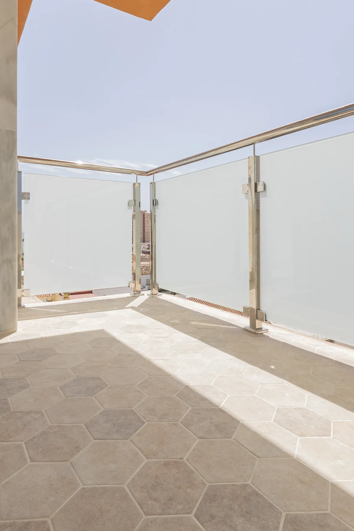 Terraza con barandilla de cristal y suelo hexagonal, reforma en Fuengirola