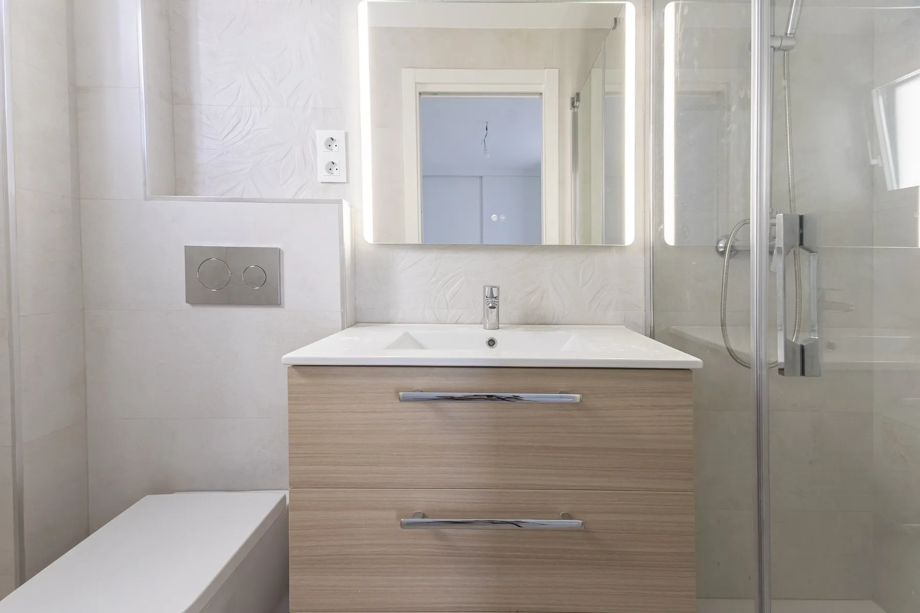 Baño con revestimiento en tonos beige, piso reformado en Fuengirola