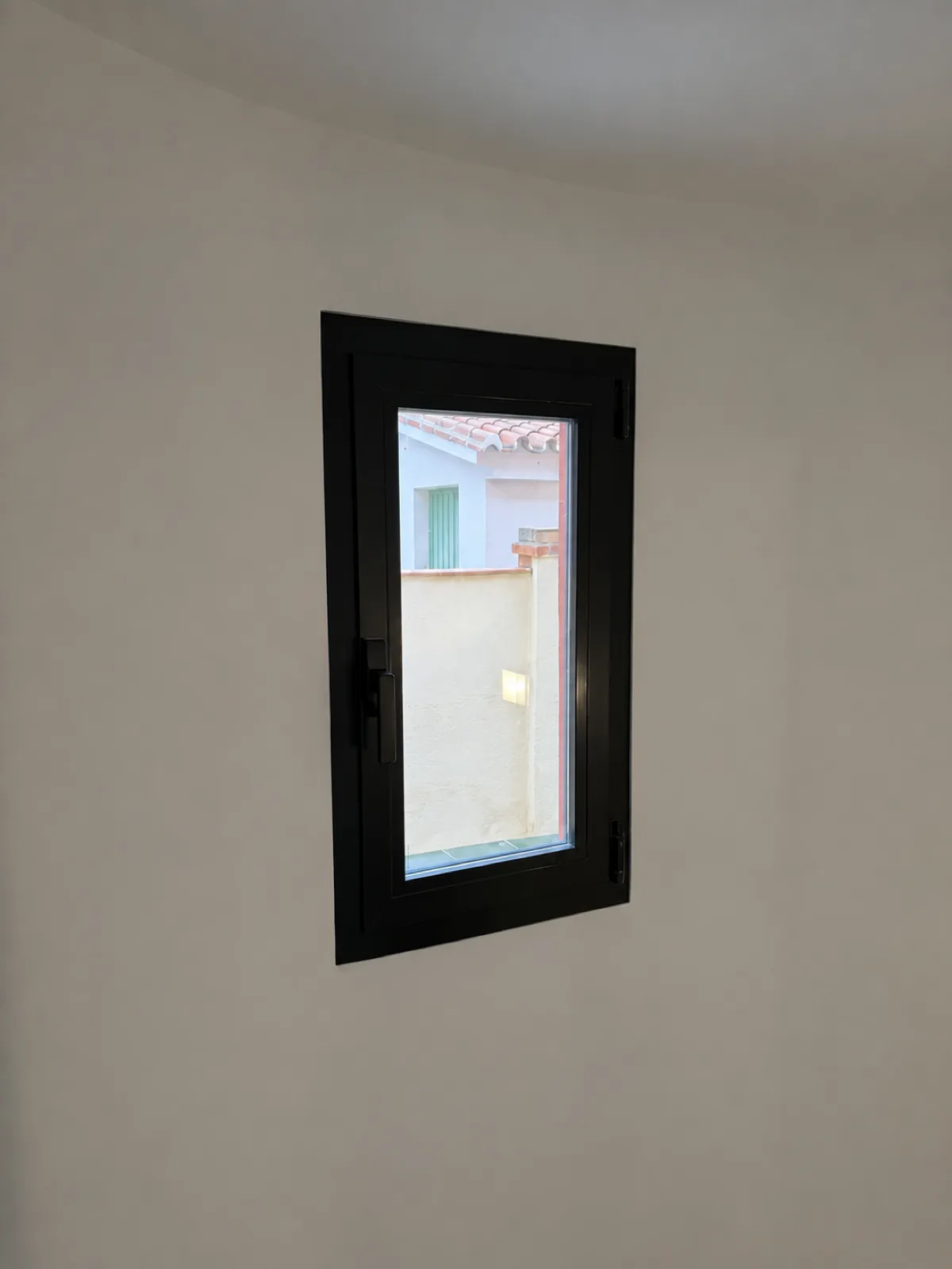 Detalle de ventana de PVC negro instalada en el hueco del antiguo pavés