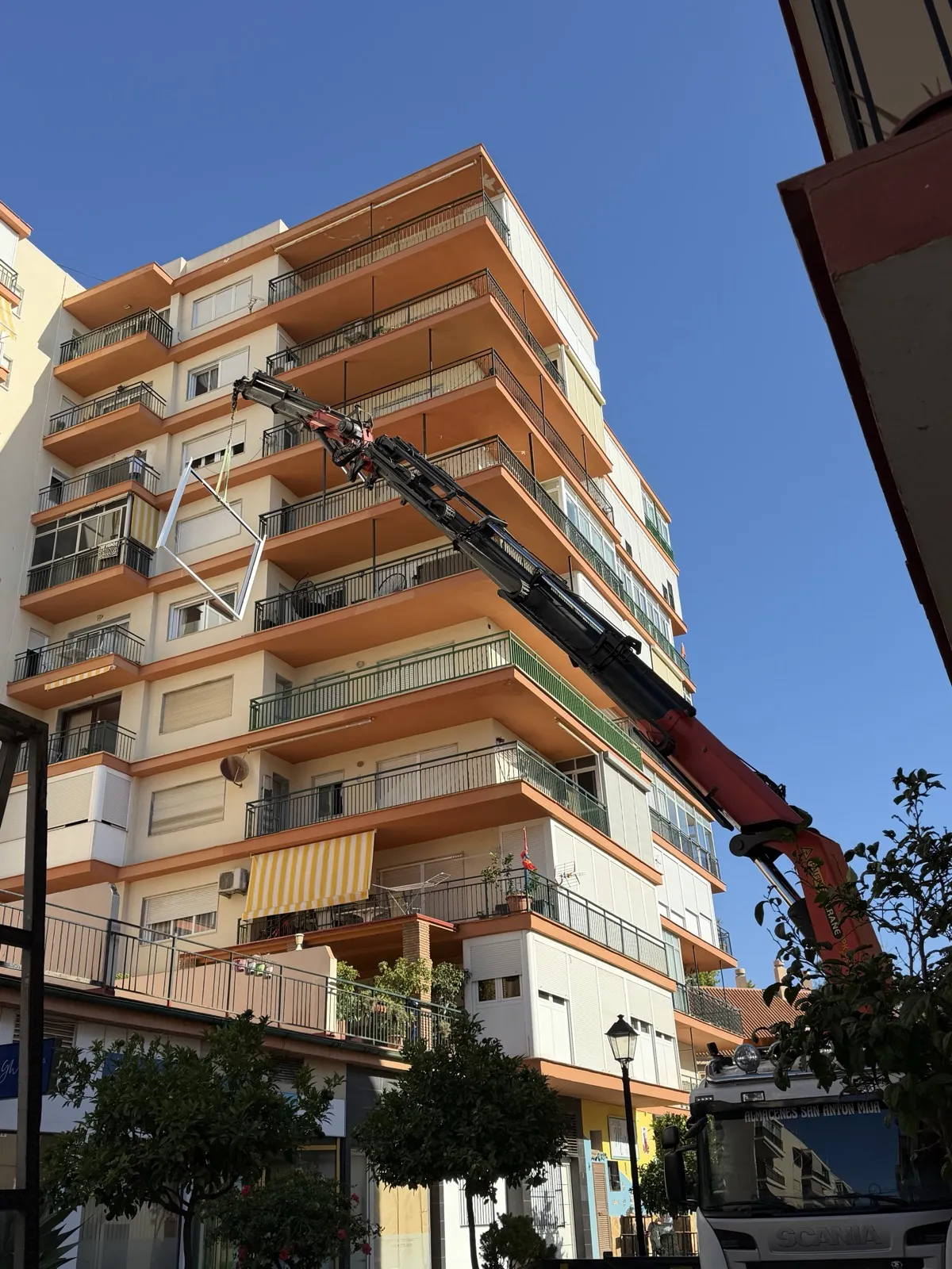 Barandilla de aluminio siendo izada con grúa hasta un balcón de un edificio
